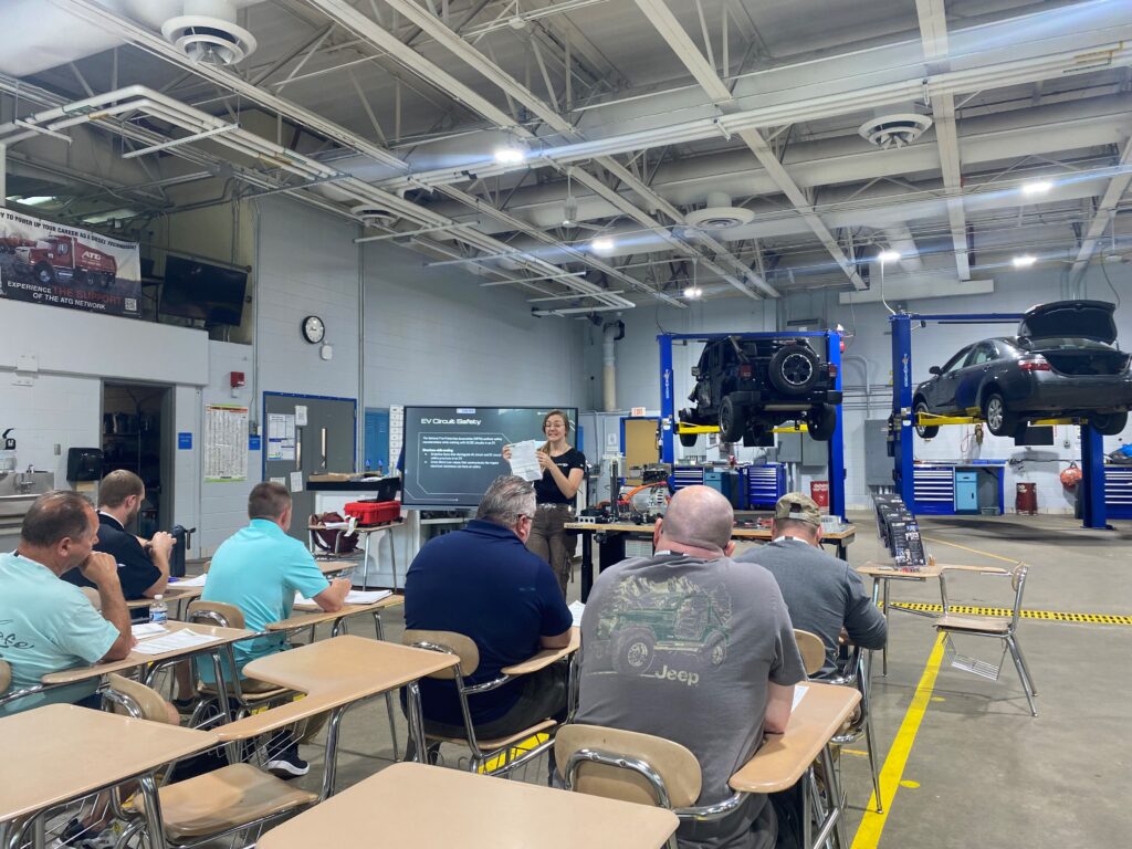 A woman from presenting to teachers about electric vehicles at an auto shop at a conference.
