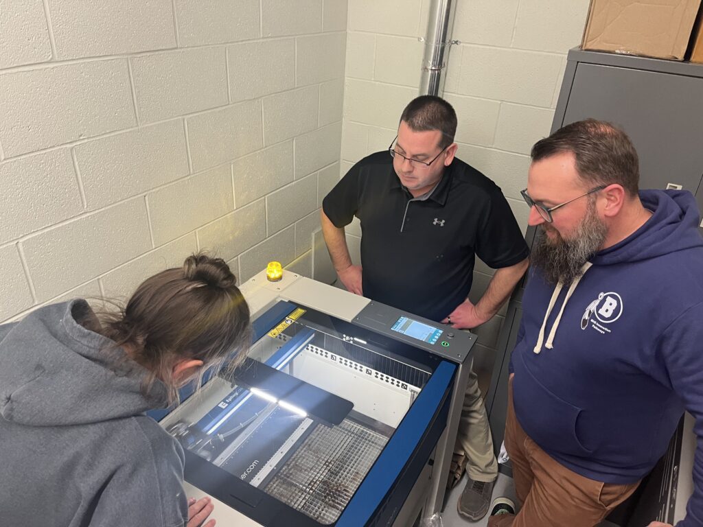 AET Labs and instructors watching an Epilog laser at STEM workshop at Bartlett High School.