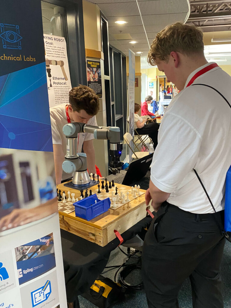 Student displaying a Universal Robots collaborative robot playing chess at the SkillsUSA Massachusetts competition.