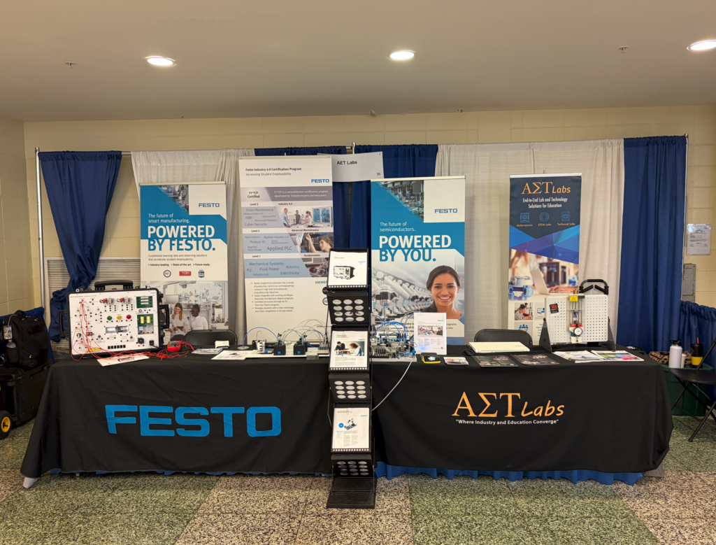  A table with banners for AET Labs and Festo with equipment on it at a conference.